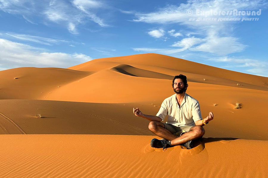 Meditando abbraciando il sole sopra le dune di Merzouga Marocco nel deserto del Sahara Explorers Around