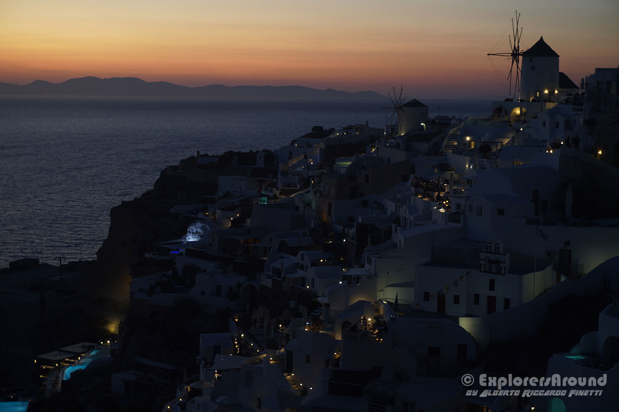 tramonto dal castello veneziano di Oia sull'isola di Santorini con vista sul mulino a vento e il mare explorers around